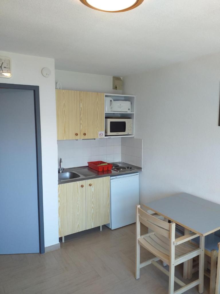 une cuisine avec une table et une cuisinière four supérieur dans l'établissement La Voile - Pendine 2 - Puy Saint Vincent - Hautes Alpes, à Puy-Saint-Vincent