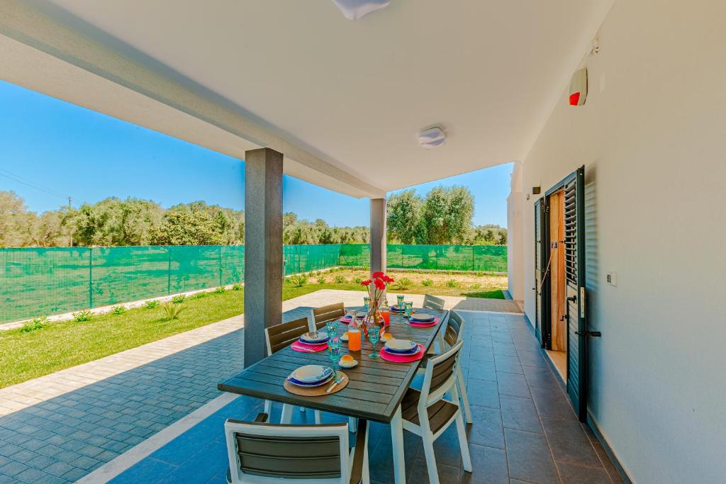 une table et des chaises en bois sur une terrasse dans l'établissement Villa Euframia, à San Vito dei Normanni
