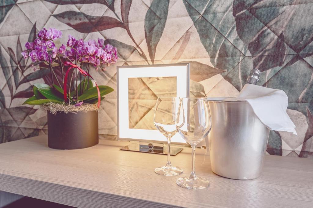 - une table avec deux verres à vin et une photo dans l'établissement Hotel Cesare Augustus, à Lido di Jesolo