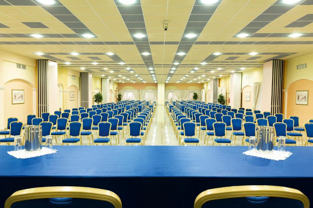 une grande pièce avec des chaises bleues et une longue table dans l'établissement Club Hotel Marina Beach, à Orosei