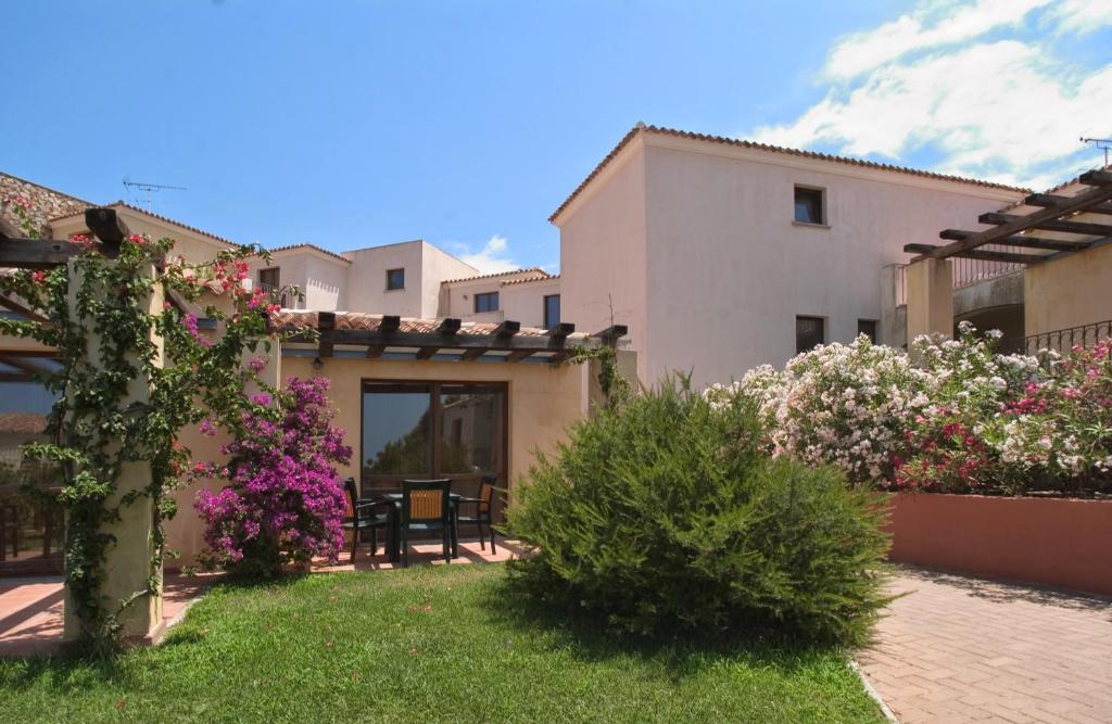 une cour avec une maison et quelques fleurs dans l'établissement Club Esse Gallura, à Aglientu