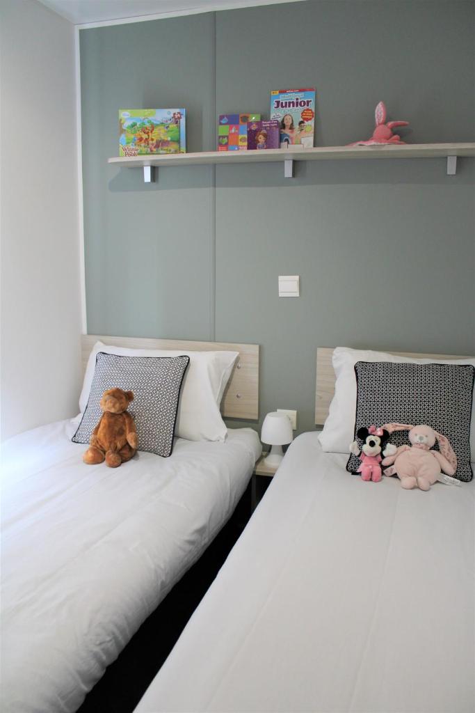 2 lits avec des animaux farcis assis sur eux dans une pièce dans l'établissement MOBILHOME 3 CH CAMPING 4*, à Onzain