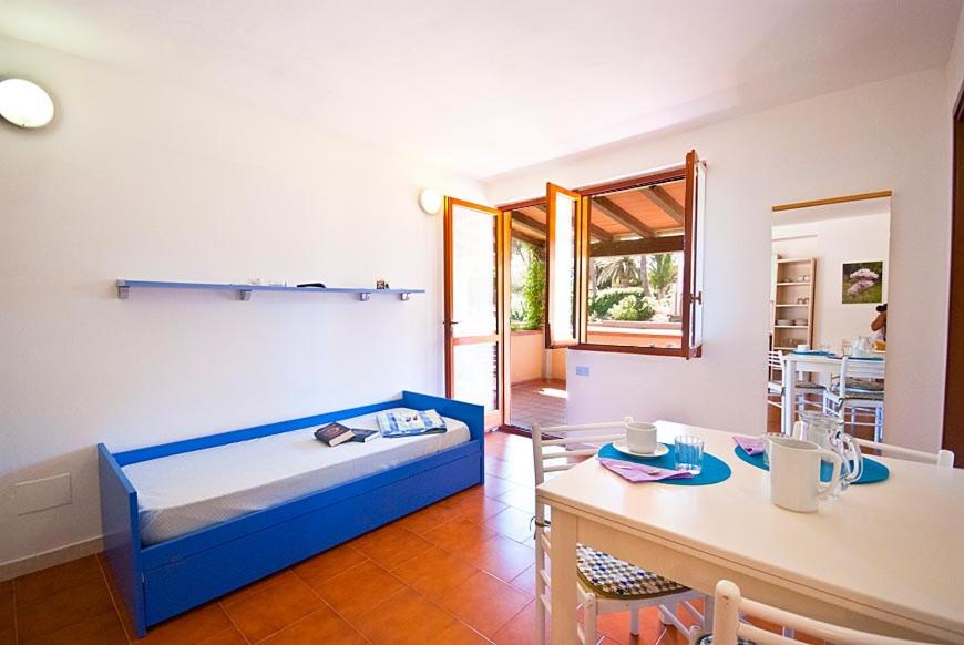 Cette chambre comprend un lit bleu, une table et une table. dans l'établissement Casa Del Golfo, à Lacona