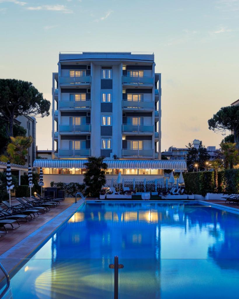 un hôtel avec une piscine devant un bâtiment dans l'établissement Hotel Delle Rose, à Lido di Jesolo