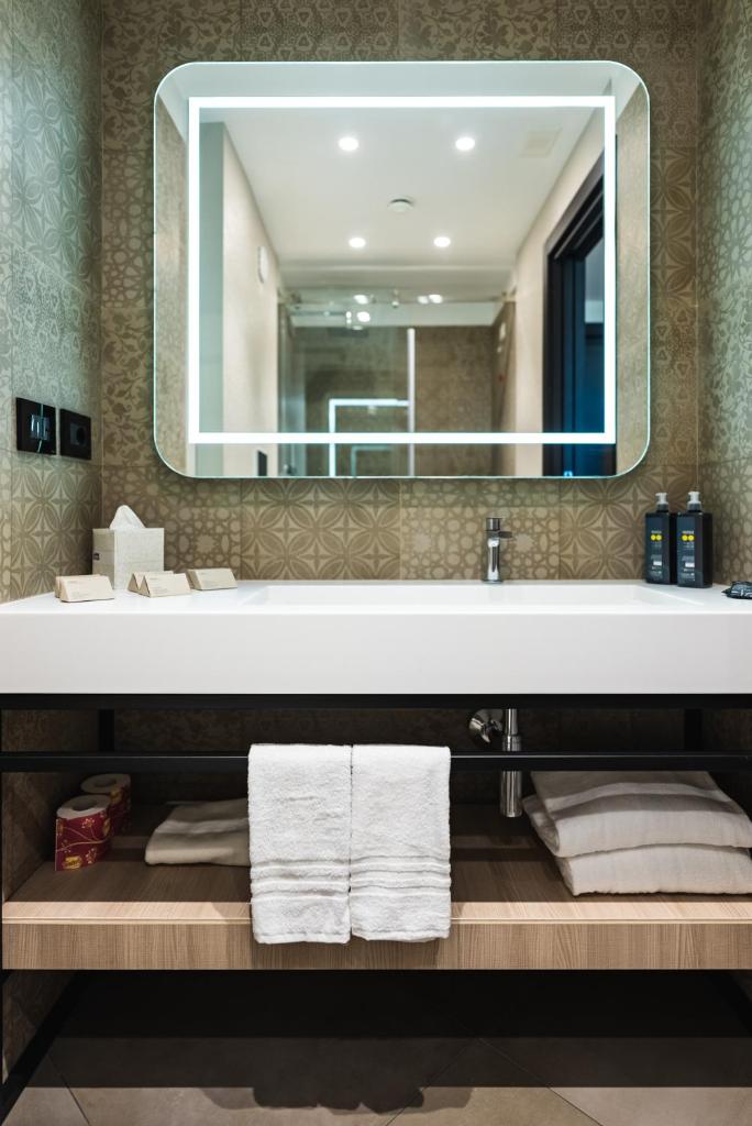 une salle de bain avec un lavabo avec un miroir et des serviettes dans l'établissement Salina Hotel, à Tarente