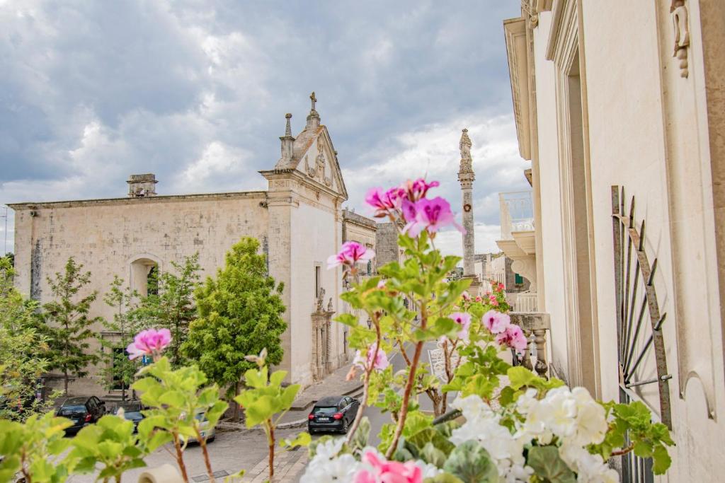 un vieux bâtiment avec des fleurs roses devant lui dans l'établissement Hotel Belami, à Maglie