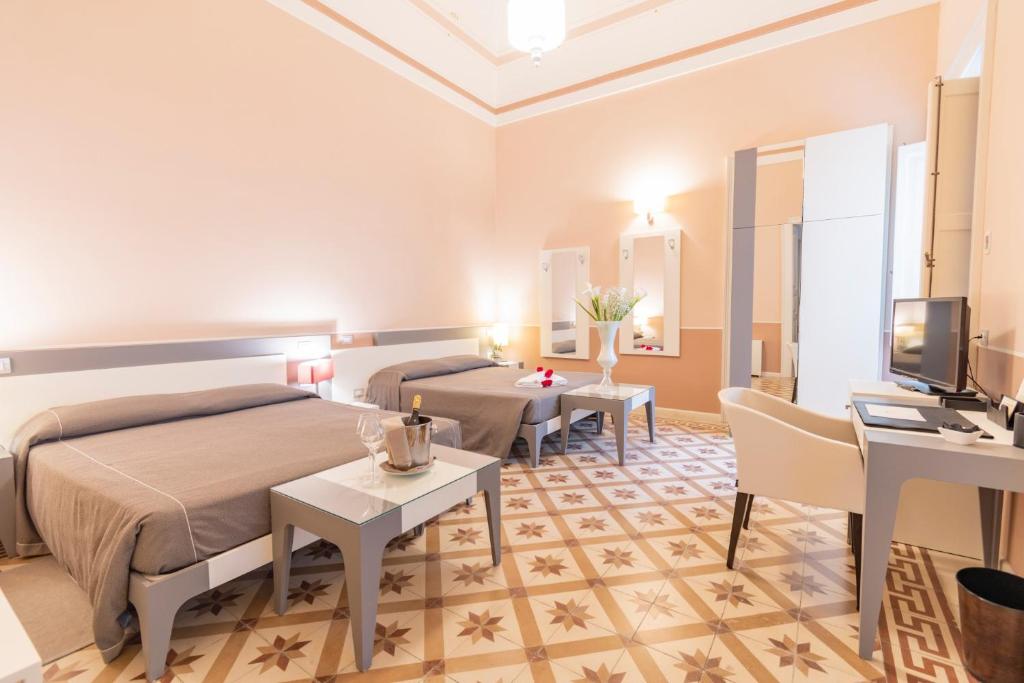 une chambre avec un lit, un bureau et une télévision dans l'établissement Hotel Belami, à Maglie