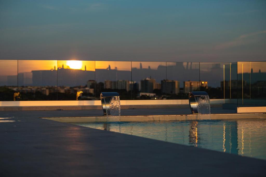 une piscine avec des fontaines d'eau devant une ville dans l'établissement Salina Hotel, à Tarente