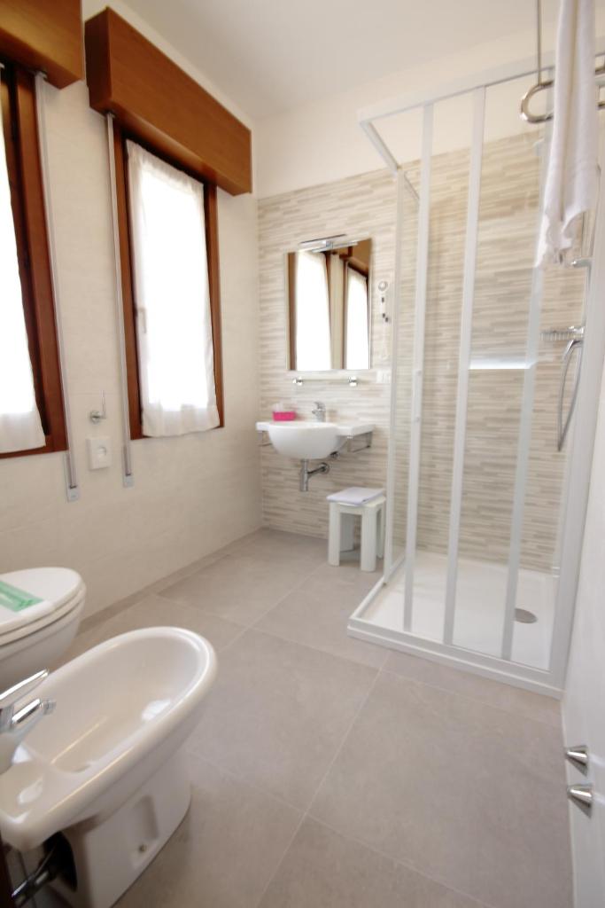 une salle de bain avec un lavabo, des toilettes et une douche dans l'établissement Hotel Serenella, à Lido di Jesolo 67 autres photos