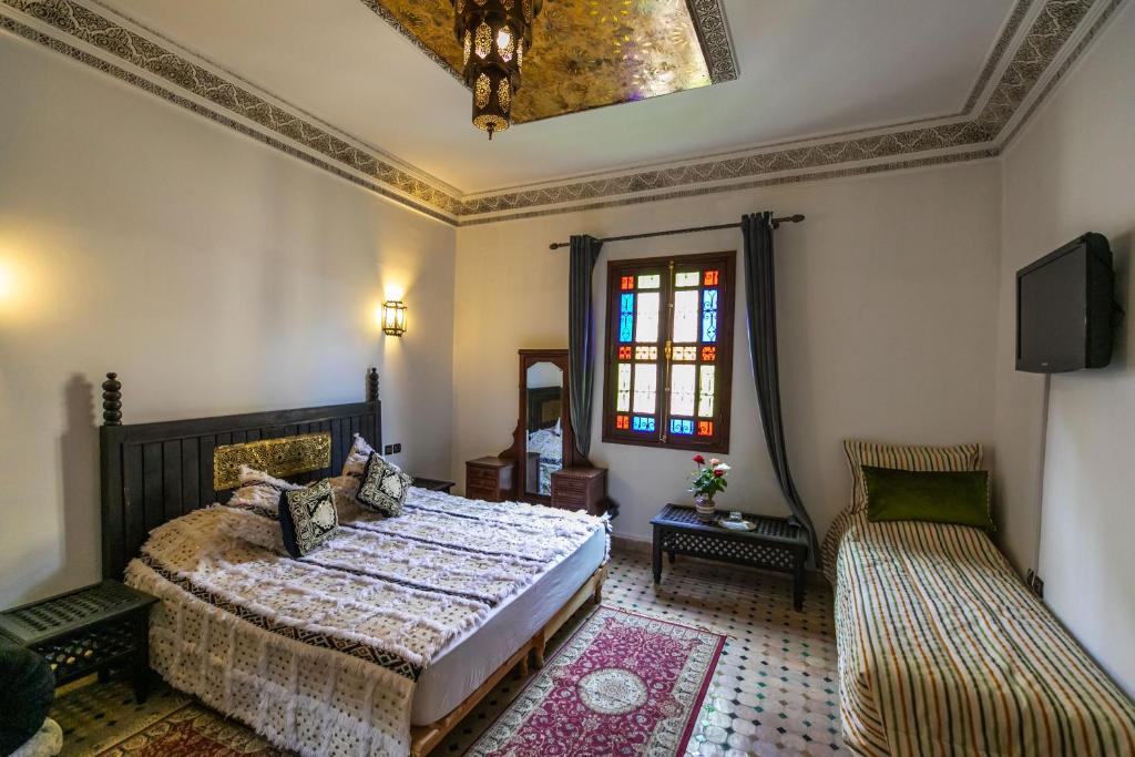 une chambre avec un lit, une fenêtre et un canapé dans l'établissement Riad Jardin Chrifa, à Fès