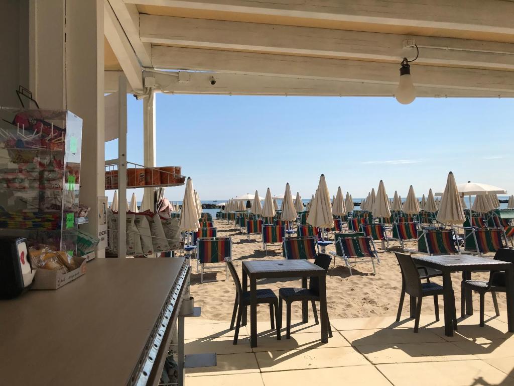 - une plage avec des tables, des chaises et des parasols dans l'établissement HOTEL FLYING, à Pesaro