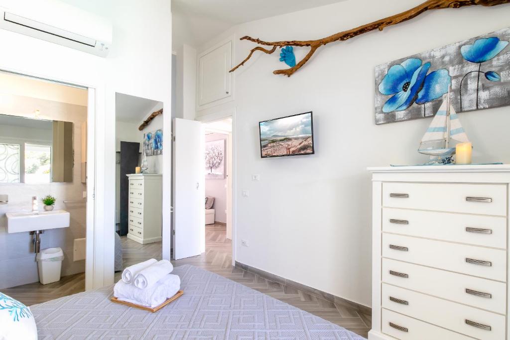 La salle de bains est pourvue d'un lavabo et d'une commode blanche. dans l'établissement SUNSET BAY POOL VILLA SARDINIA with private heated pool, jacuzzi, counter-current swimming, à Valledoria