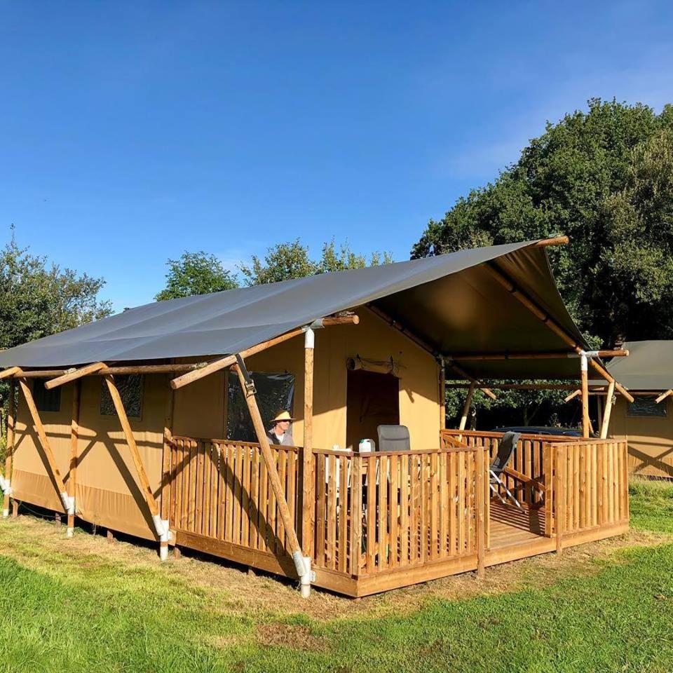 une grande tente avec une terrasse en gazon dans l'établissement Safaritent Glamping Normandie, à Longueville