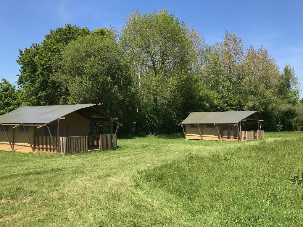 Deux tentes dans un champ planté d'arbres en arrière-plan dans l'établissement Safaritent Glamping Normandie, à Longueville