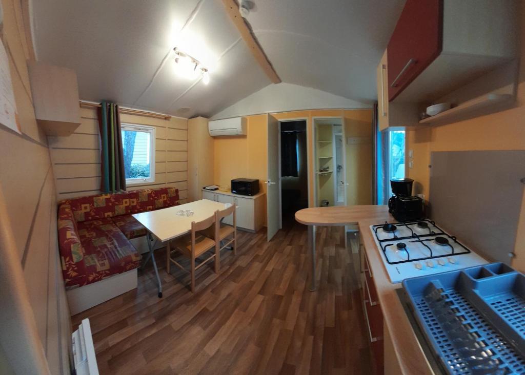 Cette petite maison dispose d'une cuisine et d'une table. dans l'établissement Mobil home climatisé 5 pers 11210 port la nouvelle, à Port-la-Nouvelle