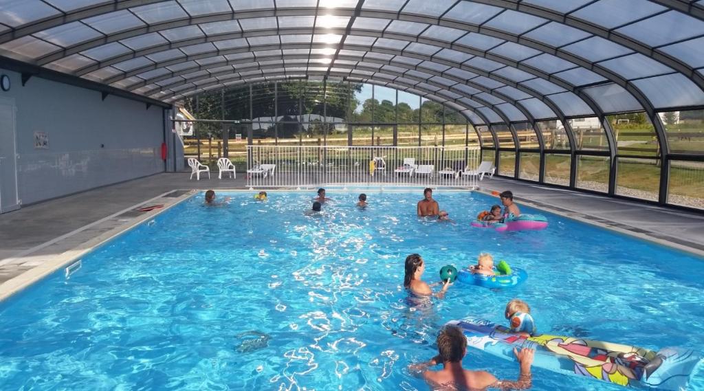 un groupe de personnes nageant dans une piscine dans l'établissement Safaritent Glamping Normandie, à Longueville