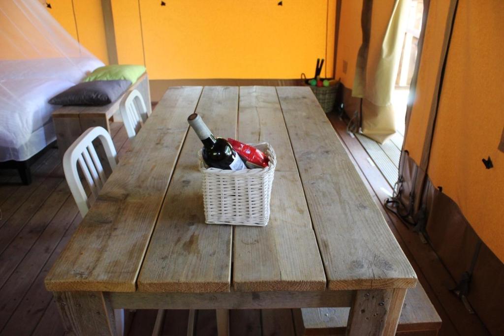- une table en bois avec une bouteille de vin dans l'établissement Safaritent Glamping Normandie, à Longueville
