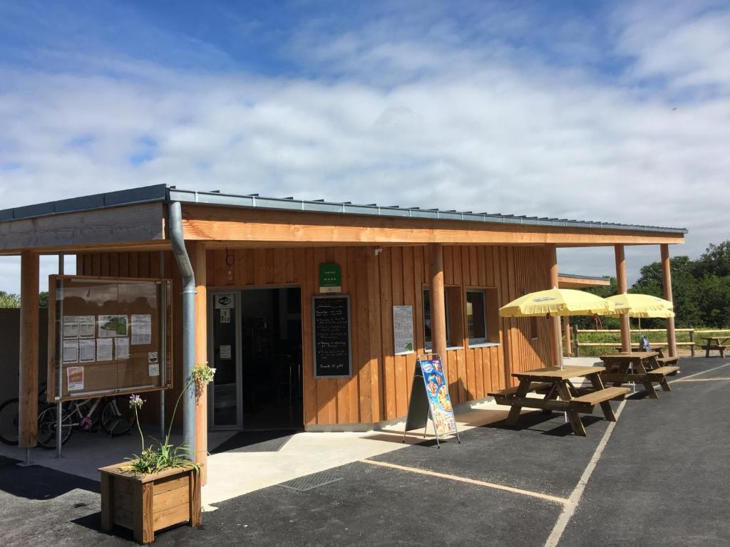 - un bâtiment en bois avec des tables de pique-nique et des parasols dans l'établissement Safaritent Glamping Normandie, à Longueville 7 autres photos