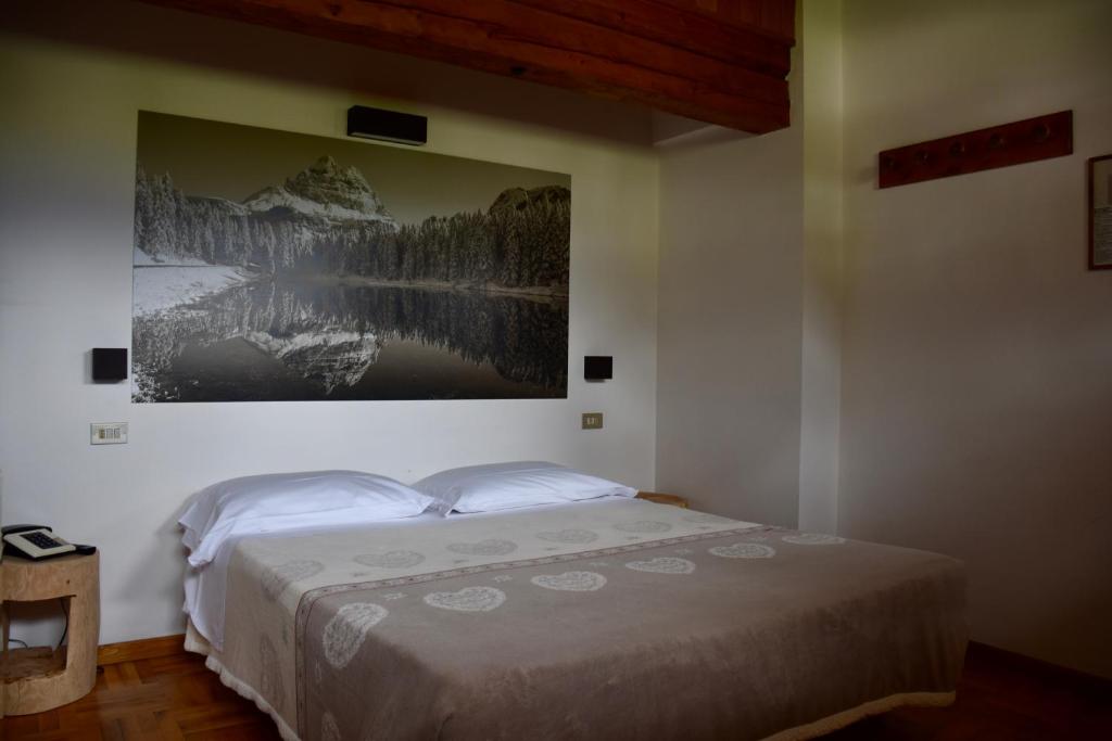 une chambre avec un lit avec un tableau sur le mur dans l'établissement Albergo Meublè Victoria, à Auronzo di Cadore