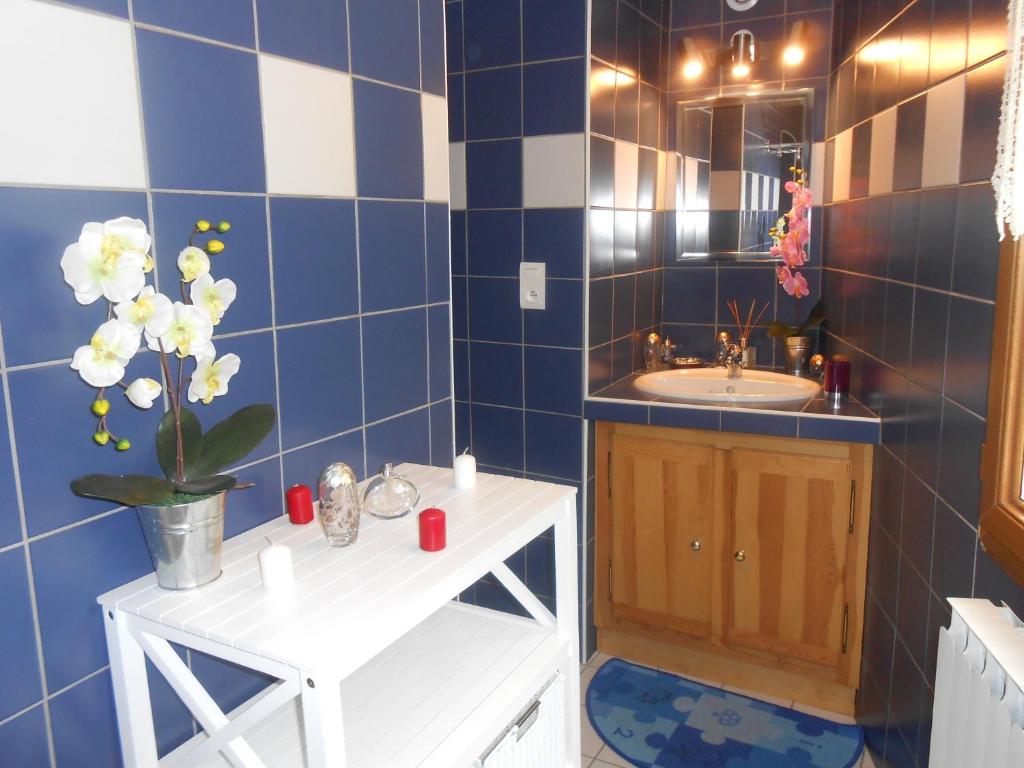 La salle de bains est pourvue de carrelage bleu, d'un lavabo et d'un miroir. dans l'établissement Gîte Vacances en Auvergne, à Saint-Géron