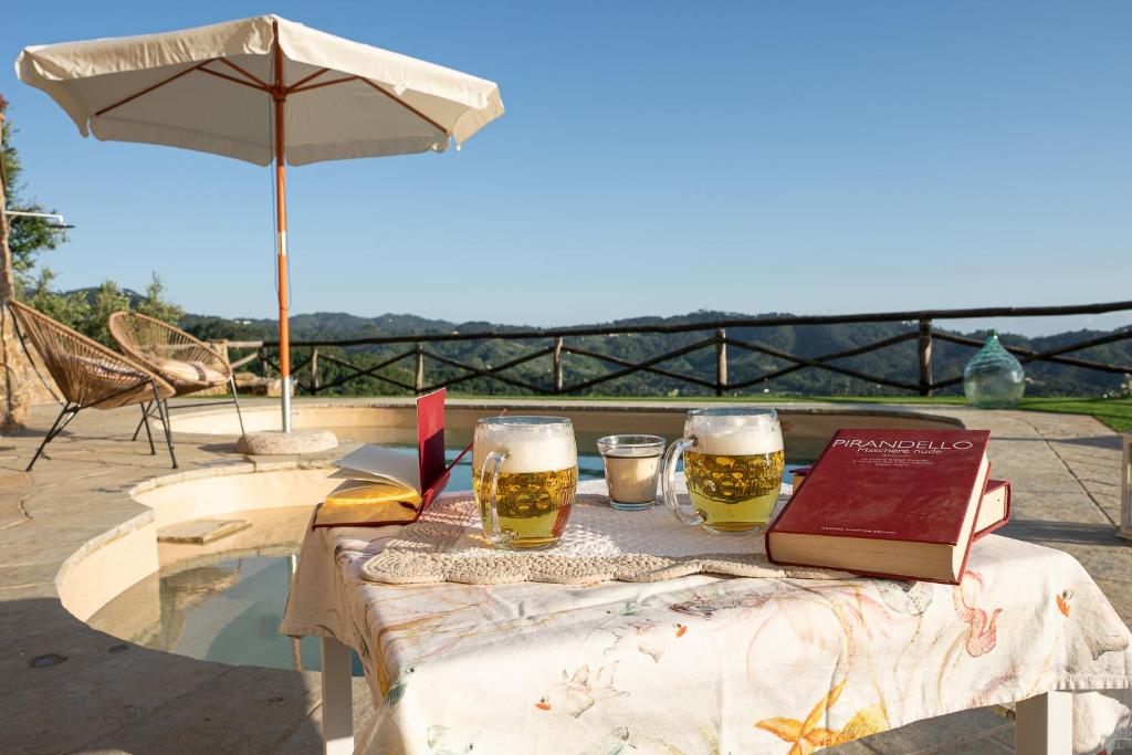 une table avec deux verres de bière et un livre dans l'établissement Villa "Il Grillo" Piscina privata, Panorama e privacy, à Camaiore