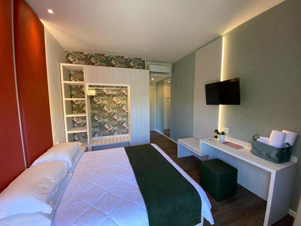 une chambre avec un lit et un bureau avec une télévision dans l'établissement Hotel Loretta & Dependance, à Cervia