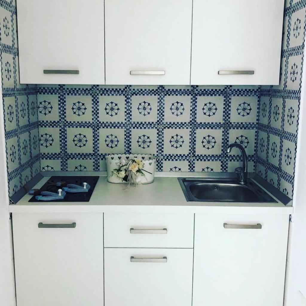 - une cuisine avec un évier et du carrelage bleu et blanc dans l'établissement Villa Spring, à Meta