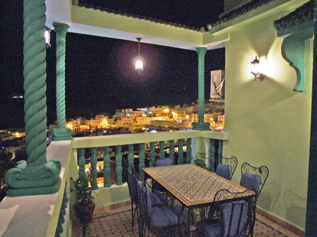 un balcon avec une table et une vue sur une ville dans l'établissement Al Andaloussiya Diyafa, à Moulay Idriss Zerhoun