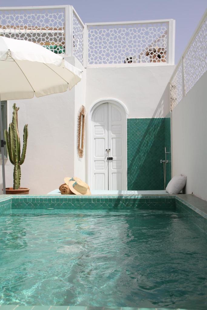 - une piscine dans une maison avec un cactus dans l'établissement Riad Helen, à Marrakech