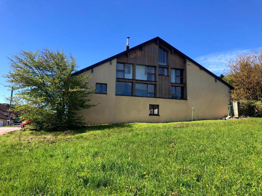 une maison sur une colline herbeuse avec un arbre dans l'établissement Gîte comme à la maison -12 pers- La Cabiote, à Les Piards