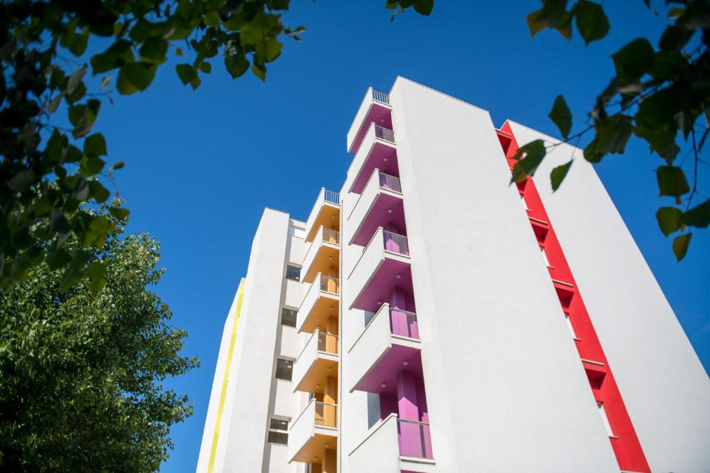 un bâtiment avec des balcons colorés face à un ciel bleu dans l'établissement Hotel Rainbow ***S, à Rimini