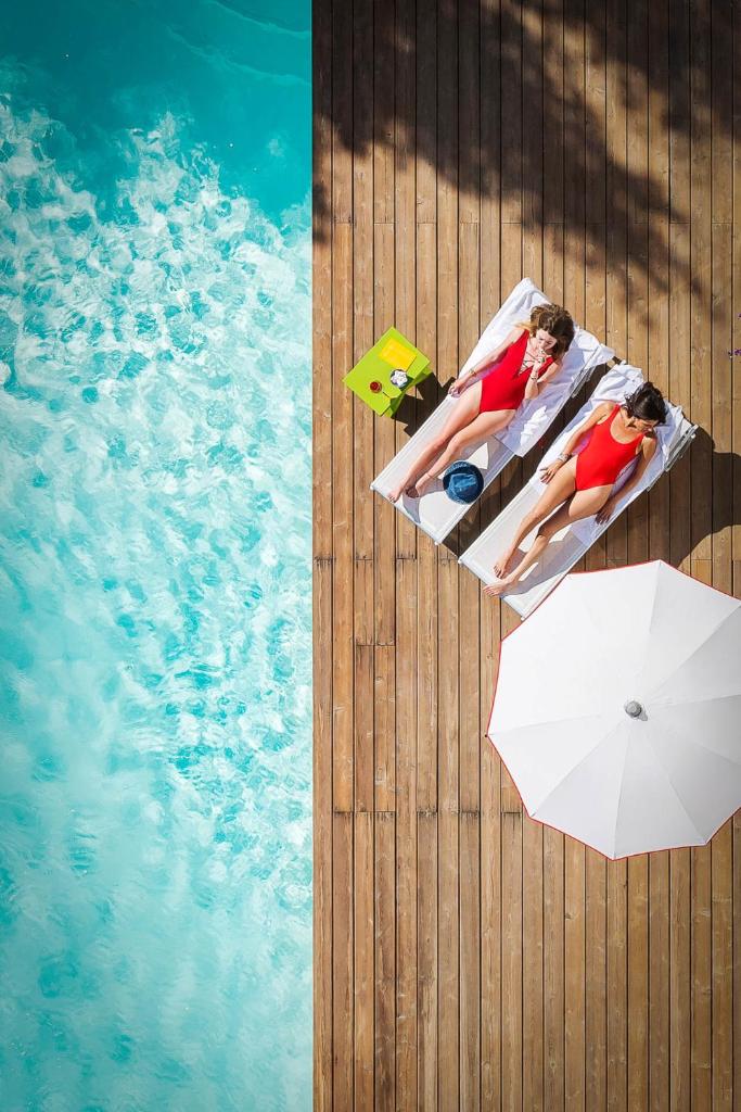 d'un homme et d'une femme dormant dans une piscine avec un parasol dans l'établissement Hotel Rainbow ***S, à Rimini