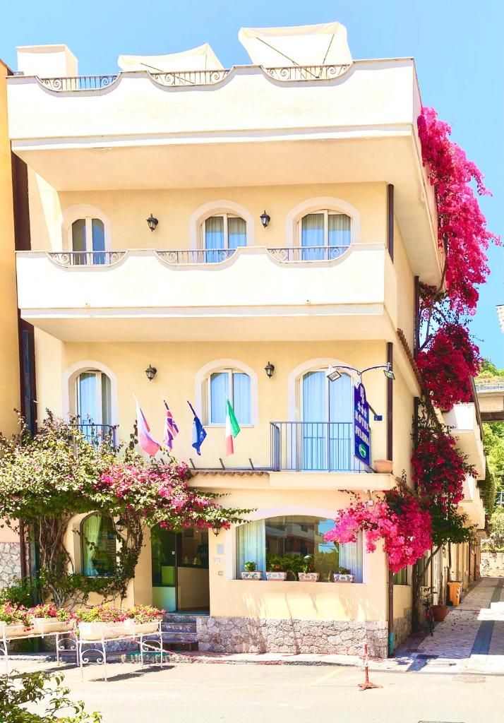 un bâtiment avec des fleurs devant lui dans l'établissement Hotel Sylesia, à Letojanni
