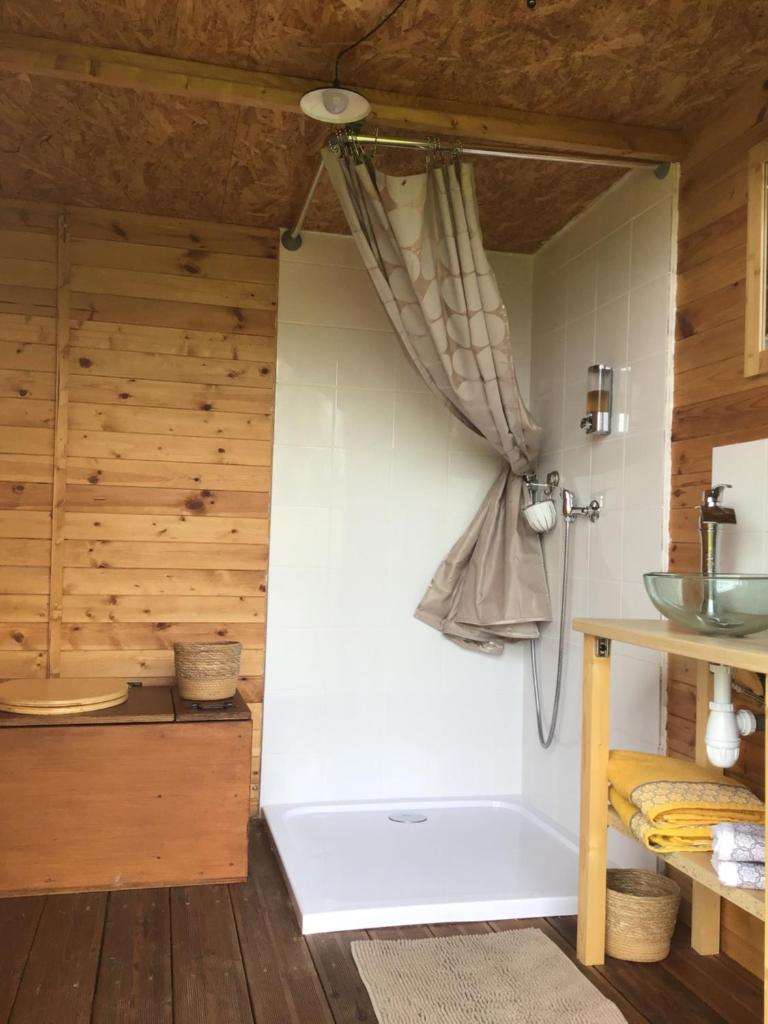 - une cuisine avec des murs en bois et une porte avec un rideau dans l'établissement Yourtes Lacroutz, à Nassiet