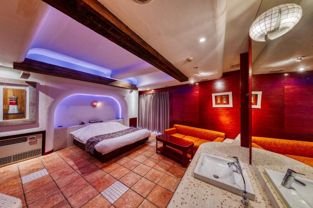 - une chambre avec un lit, un lavabo et un canapé dans l'établissement Hotel Lotus Chiba -Adult Only, à Yachiyo