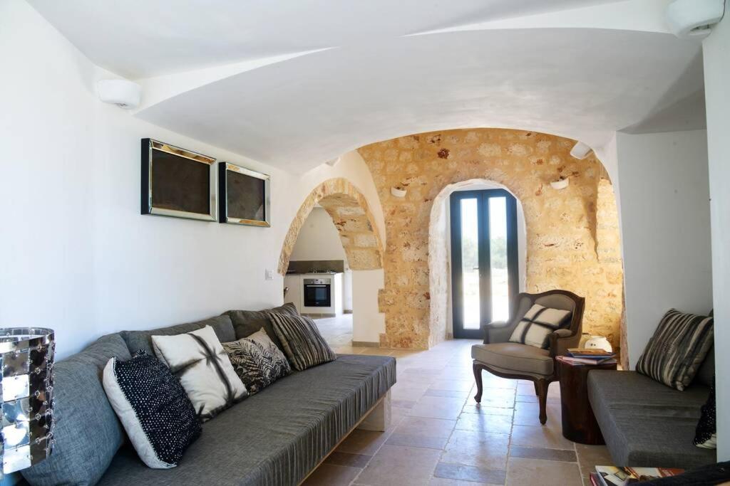 un salon avec un canapé et une chaise dans l'établissement trullo and lamia cinera, à Cisternino