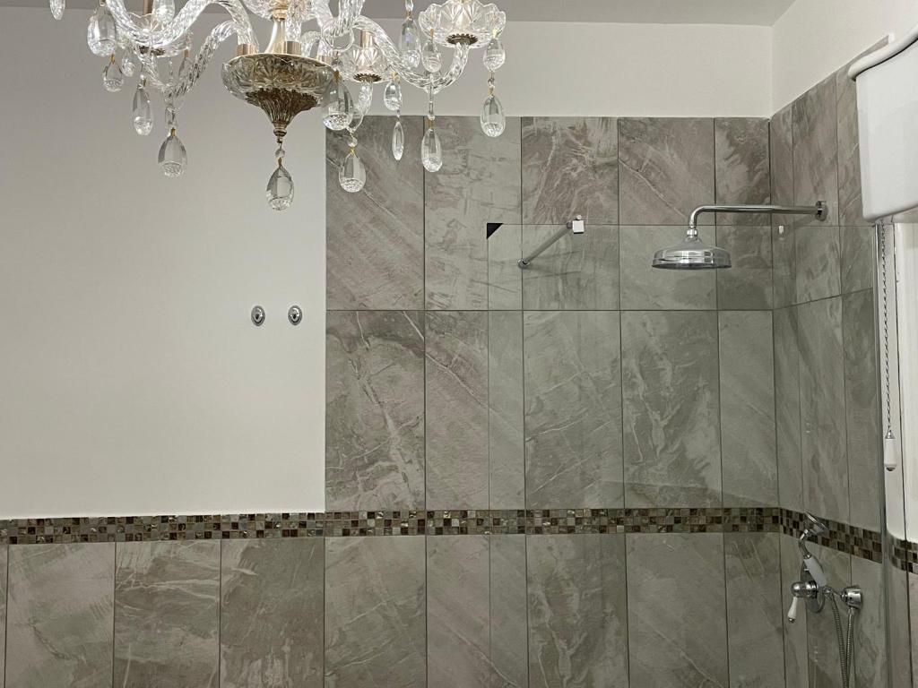 La salle de bains est pourvue d'une douche et d'un lustre. dans l'établissement luxury villa Arianna, à Tarano