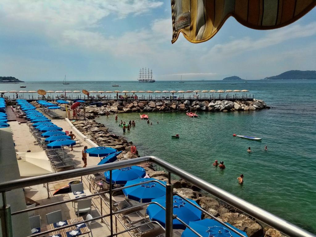 - une plage avec des parasols bleus et des personnes dans l'eau dans l'établissement Hotel San Terenzo, à Lerici