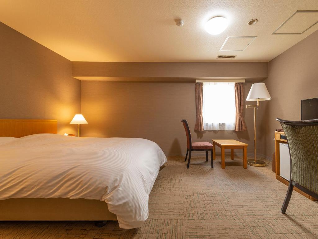 une chambre d'hôtel avec un lit, un bureau et une chaise dans l'établissement Noboribetsu Manseikaku, à Noboribetsu