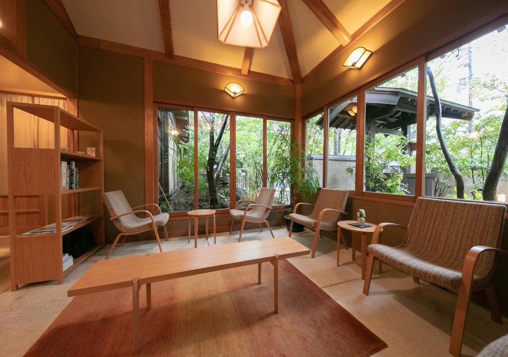 une chambre avec des chaises, des tables et des fenêtres dans l'établissement Yufuin Onsen Hinoharu Ryokan, à Yufu