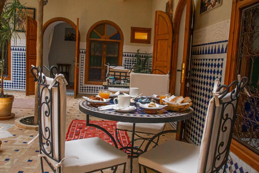 - une table avec de la nourriture dans une pièce avec des chaises dans l'établissement Riad Dar Tamlil, à Marrakech