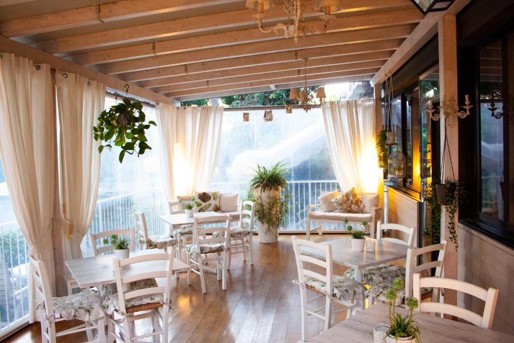 une salle à manger avec tables, chaises et fenêtres dans l'établissement Hotel Loretta & Dependance, à Cervia