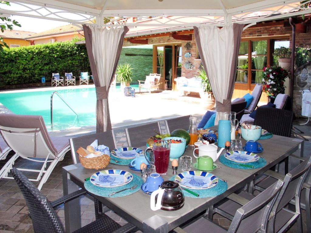 - une table pour le petit-déjeuner à côté de la piscine dans l'établissement Villa Capo Corso by Interhome, à Corsanico-Bargecchia