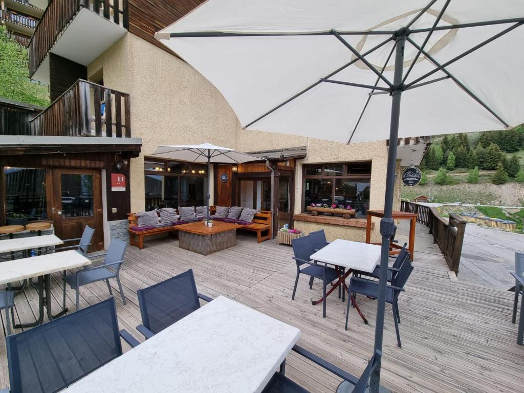 un patio extérieur avec tables, chaises et un parasol dans l'établissement Hotel Le Beau Site, à Auris