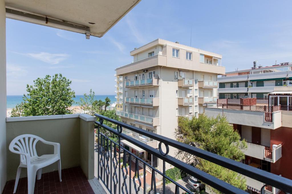 - un balcon avec une chaise blanche et un bâtiment dans l'établissement Hotel Christian Ideale Per Famiglie, à Riccione