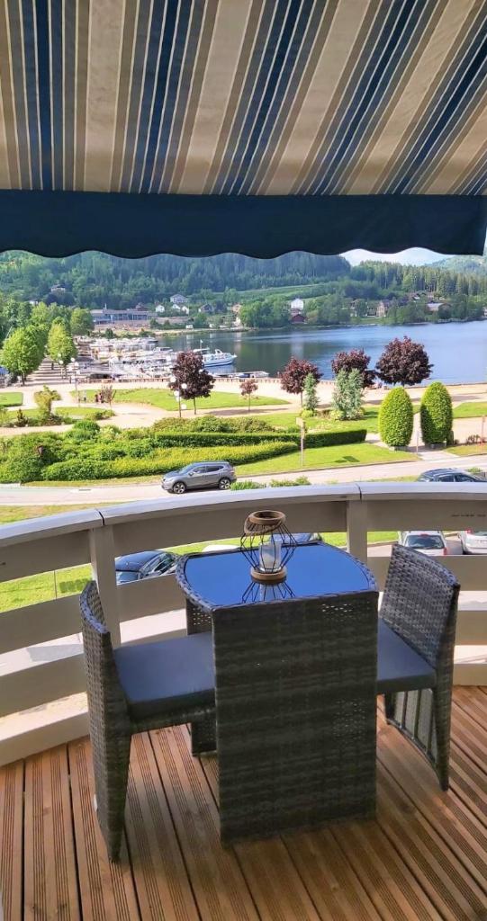 une table et des chaises sur une terrasse avec vue sur l'eau dans l'établissement Miellerie du lac, à Gérardmer
