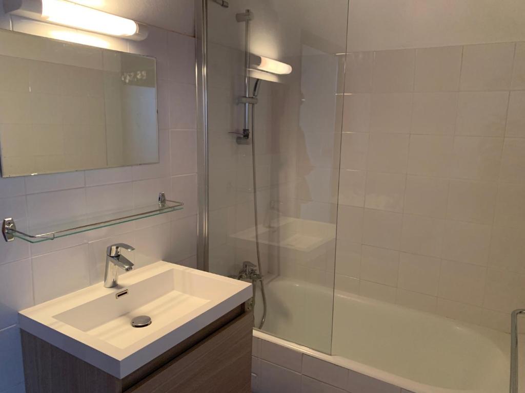 une salle de bain blanche avec un lavabo et une douche dans l'établissement Gîte du Dolmen de l'Hom, à Le Massegros