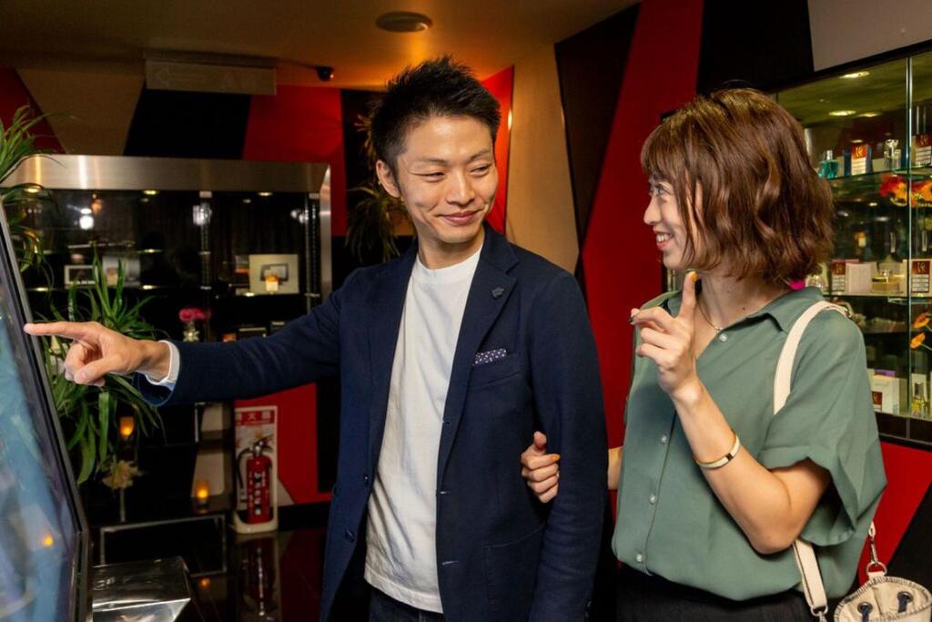Un homme et une femme qui regardent une voiture dans un magasin dans l'établissement Hotel Benkyo Beya Amagasaki, à Amagasaki
