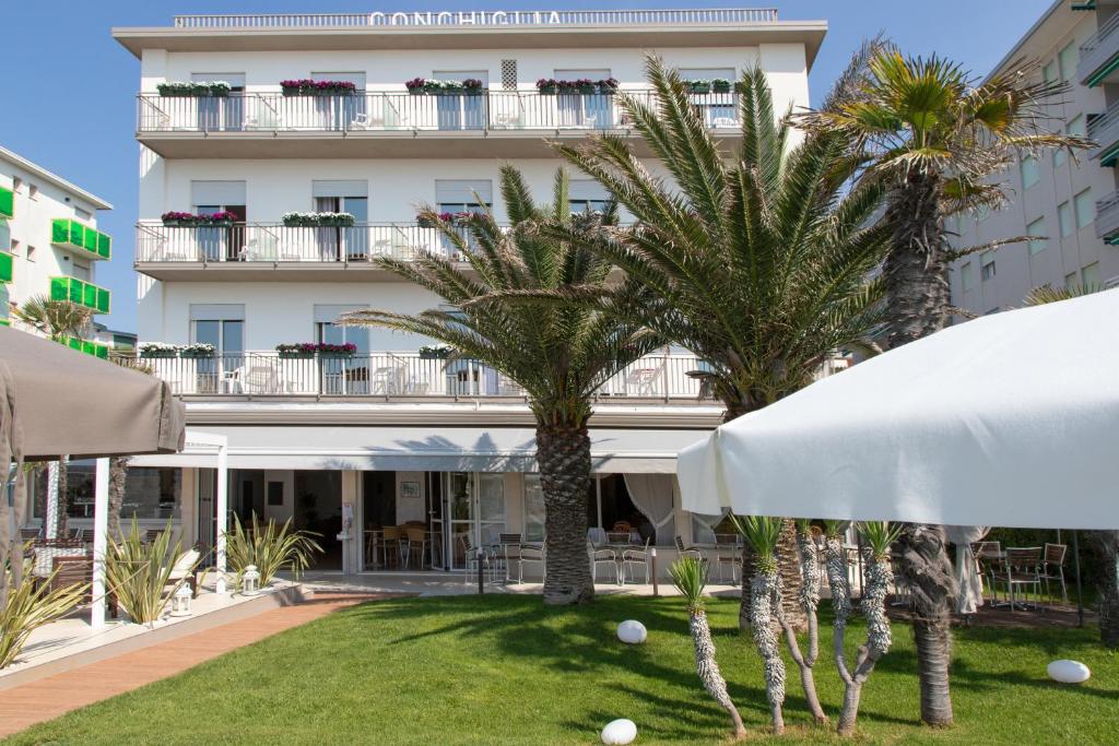 un hôtel avec des palmiers devant un bâtiment dans l'établissement Hotel Conchiglia, à Lido di Jesolo