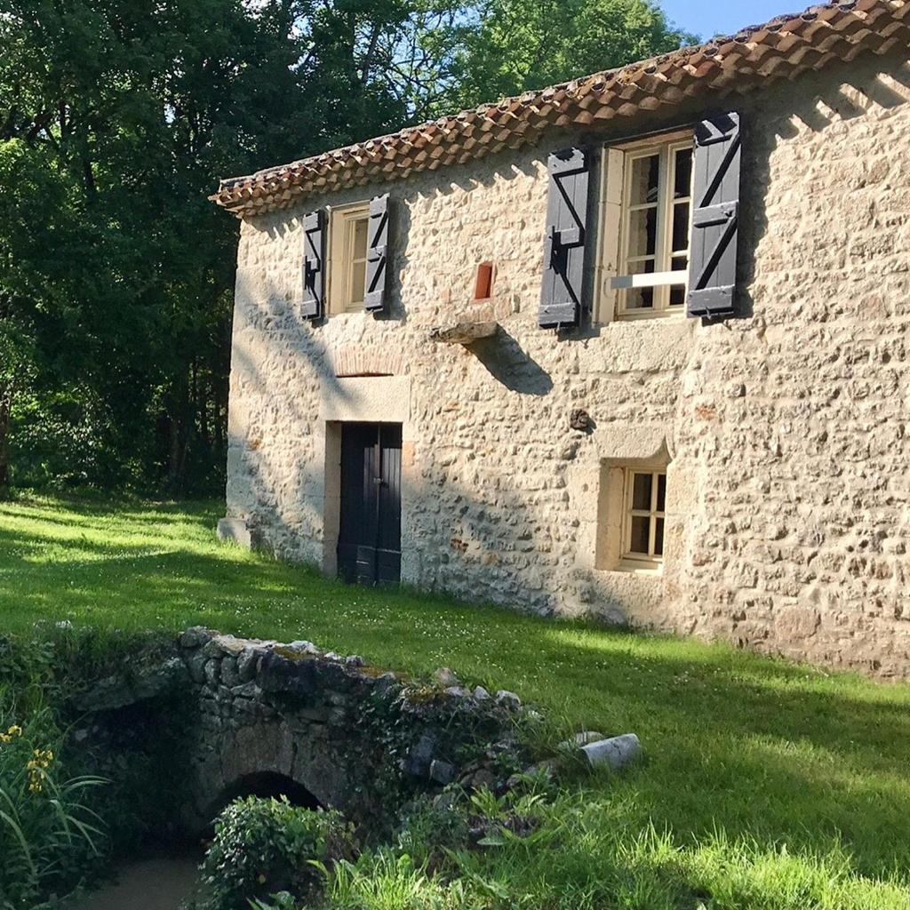 une maison en pierre dotée d'une porte et d'une pelouse. dans l'établissement gîte de charme avec piscine, à Montpezat-de-Quercy